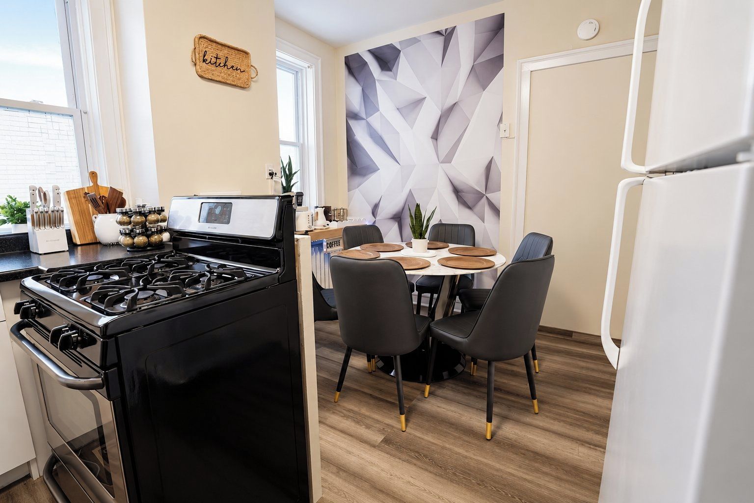 A modern kitchen with a gas stove, a dining table with chairs, and a decorative wall.