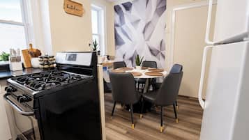 A modern kitchen with a gas stove, a dining table with chairs, and a decorative wall.