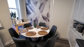 A dining area with a round table set for six, surrounded by black chairs. - 6BR Apt • Workspace • Near Lakefront + Red Line (Chicago)