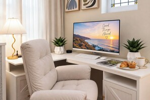 A modern office desk with a computer, keyboard, mouse, and a motivational quote on the screen. There are two potted plants, a lamp, and a cup of coffee on the desk.