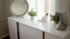 A white vanity with a round mirror, a remote control holder, and two potted plants. - 6BR Apt • Workspace • Near Lakefront + Red Line (Chicago)