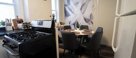A modern kitchen with a gas stove, dining table, chairs, and a decorative wall.