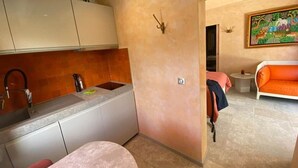 Ett kompakt bostadsutrymme med ett litet kök, en matplats och en soffa.
