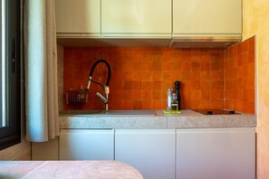 A compact kitchen with a tiled backsplash, a sink, and a faucet. - Air-conditioned studio - Terrace and Spa (Aix-en-Provence)