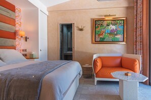 A hotel room with a bed, a sofa, a small table, a painting, and a bathroom door. - Air-conditioned studio - Terrace and Spa (Aix-en-Provence)