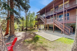 Ein mehrgeschossiges Holzgebäude mit Außentreppe, einer überdachten Terrasse und einem roten Stuhl.