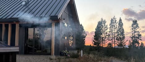 A modern house with a metal roof, a chimney, and a fire pit with flames.