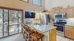 A kitchen with a large island, stainless steel appliances, wooden cabinets, and a sign that reads 'GRAND LAKE.'