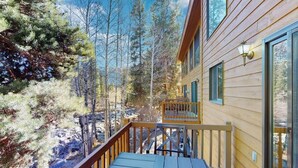A wooden cabin with a deck, surrounded by trees.