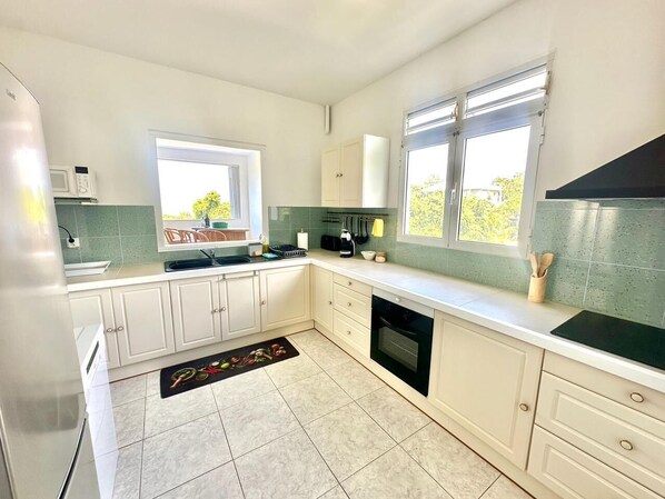 A modern kitchen with white cabinets, a black stove, and a window providing natural light.