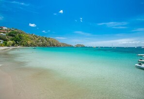 Una playa con agua turquesa cristalina, una orilla arenosa y barcos.