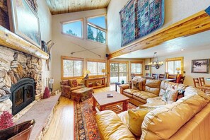A spacious living room with a stone fireplace, leather sofas, and large windows. - Dog-friendly mountain home with fireplace, firepit & ping-pong - great for kids (Tabernash)