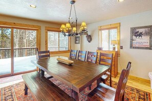 A dining area with a wooden table, chairs, a chandelier, and a deer head mounted on the wall. - Dog-friendly mountain home with fireplace, firepit & ping-pong - great for kids (Tabernash)