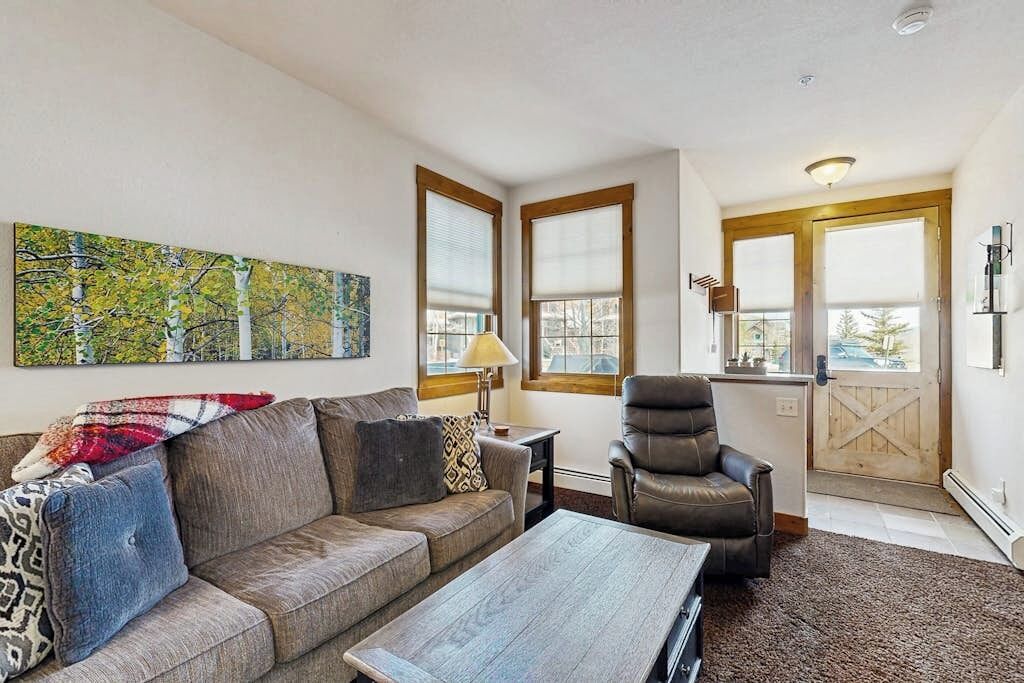Ein Wohnzimmer mit einer Couch, einem Sessel, einem Couchtisch und einem Bild an der Wand.