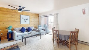 A living room with a ceiling fan, a sofa, a coffee table, and a dining table with chairs. - Spacious townhome with a scenic deck, grill & washer/dryer - near the lake (Grand Lake)
