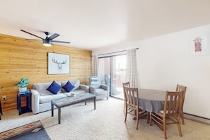 Ein Wohnzimmer mit Deckenventilator, einer Couch, einem Couchtisch und einem Esstisch mit Stühlen.