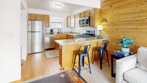 A modern kitchen with wooden cabinets, stainless steel appliances, and a central island with bar stools. - Spacious townhome with a scenic deck, grill & washer/dryer - near the lake (Grand Lake)