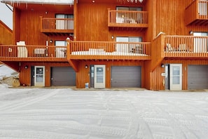 Ein mehrstöckiges Holzgebäude mit Balkonen, Garagentoren und einem mit Schnee bedeckten Gelände.