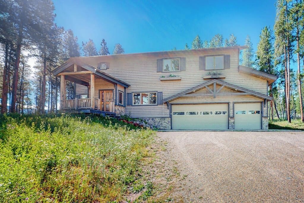 A two-story house with a covered porch, a garage, and a gravel driveway.