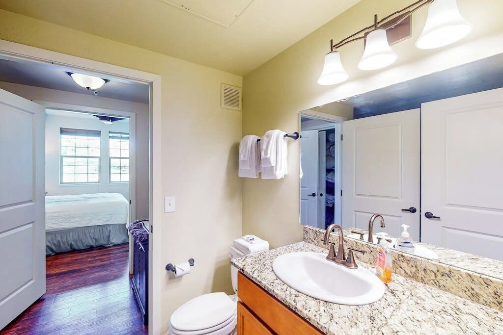 Une salle de bain équipée d’un lavabo, d’un miroir, d’un porte-serviettes et de toilettes.