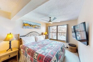 Ein Schlafzimmer mit Bett, Deckenventilator, Fenster, Gemälde und Lampe.