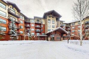 A multi-story building with a ski lodge entrance labeled 'BASE CAMP ONE,' featuring balconies and a snow-covered ground. - 310 Base Camp | Condo in Granby (Granby)
