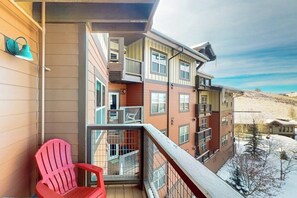 A multi-story building with balconies, a red chair, and a snowy landscape. - 310 Base Camp | Condo in Granby (Granby)