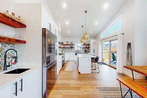 A modern kitchen with a central island, wooden flooring, and pendant lighting. - Dog-friendly golf course-front home with mtn & ski views, fireplace, & balconies (Granby)