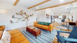 Un soggiorno moderno con un divano, un tavolino da caffè e un'originale decorazione a forma di albero sulla parete.