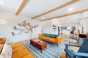 A modern living room with a sofa, coffee table, and a unique tree-shaped wall decoration. - Dog-friendly golf course-front home with mtn & ski views, fireplace, & balconies (Granby)