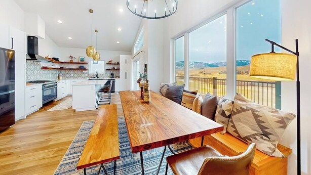 Una cucina moderna con un tavolo da pranzo in legno, una grande finestra vista e un lampadario.