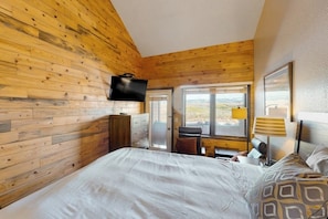 A bedroom with wooden walls, a bed, a desk, a chair, a TV, and a window with a view. - 3rd-floor condo with balcony, indoor & outdoor pools, game room, gym, W/D (Granby)