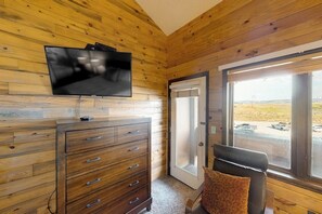 A wooden-paneled room with a TV, a dresser, a door leading outside, and a window with a view. - 3rd-floor condo with balcony, indoor & outdoor pools, game room, gym, W/D (Granby)