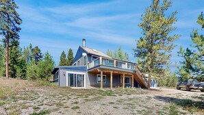 Ein zweistöckiges Haus mit einer großen Terrasse, umgeben von Bäumen.