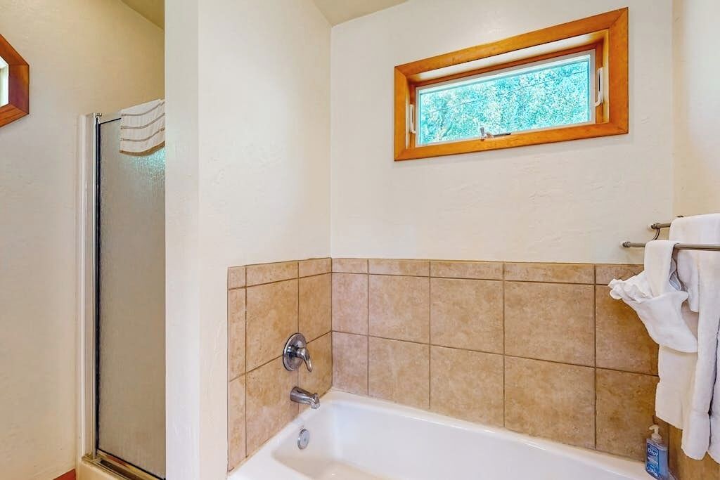 Ein Badezimmer mit Dusche, einer Badewanne, einem Fenster und einem Handtuchhalter.