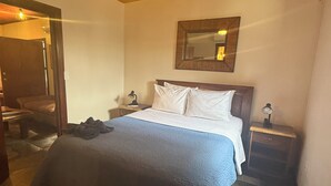 Ein Schlafzimmer mit Bett, Nachttischen, einem Spiegel und einer Deckenleuchte.