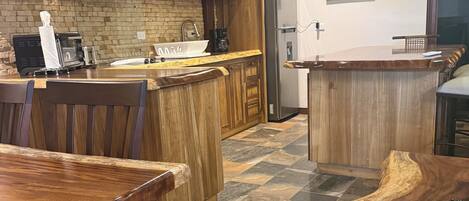 Una cocina con armarios de madera, piso de baldosas de piedra y una barra.