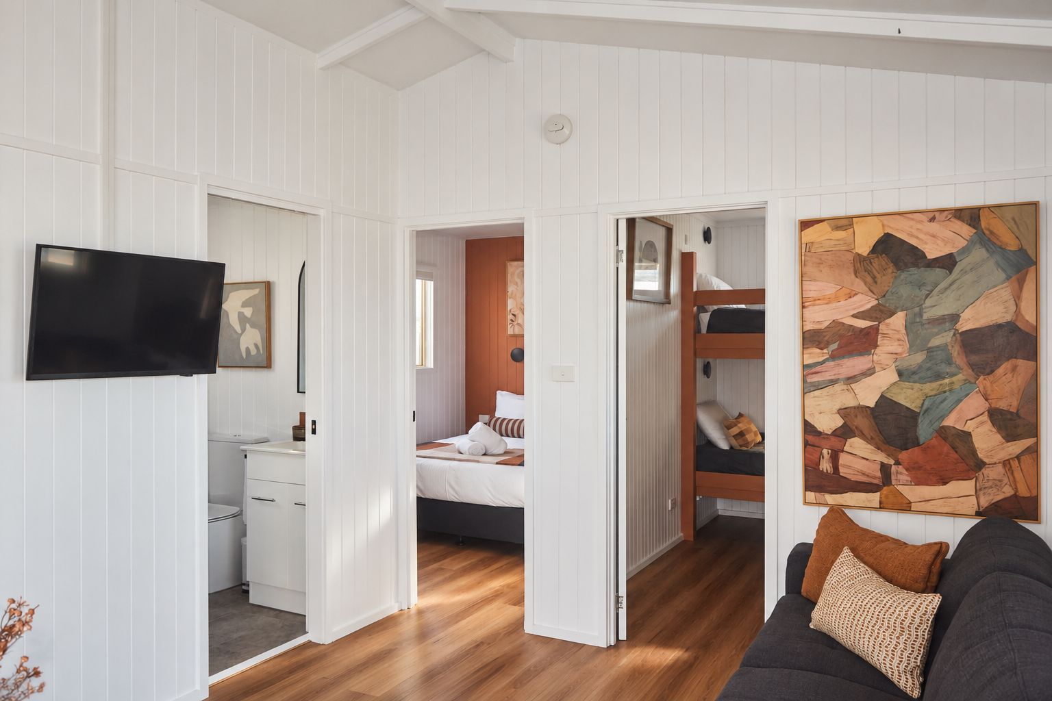 Een kamer met een bed, een televisie, een schilderij en een bank.