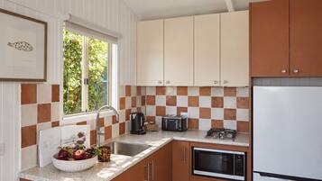 A kitchen with a sink, toaster, kettle, and a refrigerator.