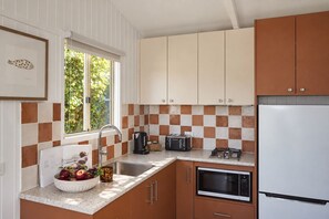 A kitchen with a sink, toaster, kettle, and a refrigerator.