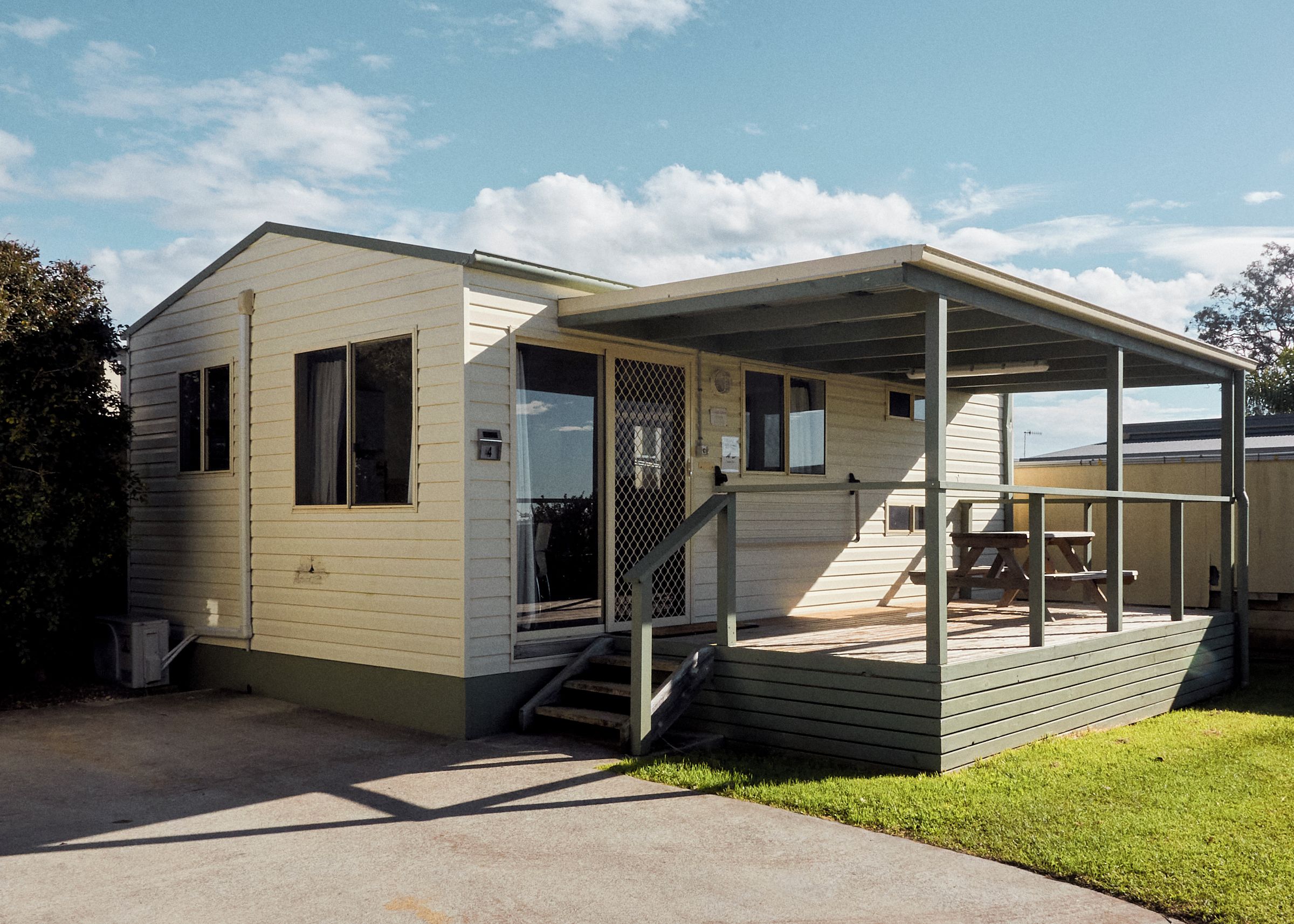 A single-story mobile home with a covered porch and a small deck.