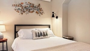 Une chambre à coucher comprenant un lit, un élément décoratif mural, une lampe et une petite table.