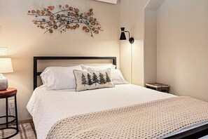 Ein Schlafzimmer mit einem Bett, einer Wanddekoration, einer Lampe und einem kleinen Tisch.