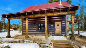 Une cabane en rondins avec un toit rouge, une véranda en bois et une enseigne portant le numéro « 48 ».