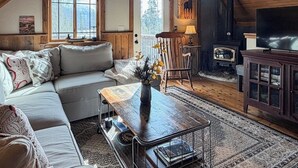 Un salon confortable avec un canapé, une table basse, une cheminée et un téléviseur.