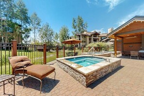 A pool area with a lounge chair, a hot tub, and a covered seating area. - Beautiful condo w/shared pools, hot tubs, & ski shuttle + private washer/dryer (Steamboat Springs)