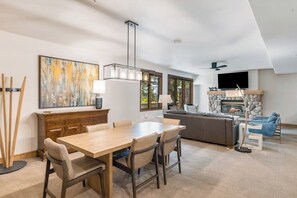 Ein modernes Wohnzimmer mit Essbereich, Kamin und großen Fenstern.