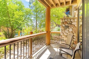 Ein überdachter Balkon mit Steinwand, Holzgeländer und zwei Stühlen.