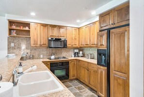 Eine Küche mit Holzausstattung, einer Mikrowelle, einem Kühlschrank, einem Herd und einem Spülbecken.