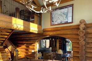 Ein Blockhaus-Interieur mit einer Holztreppe, einem Essbereich und einer Karte an der Wand.